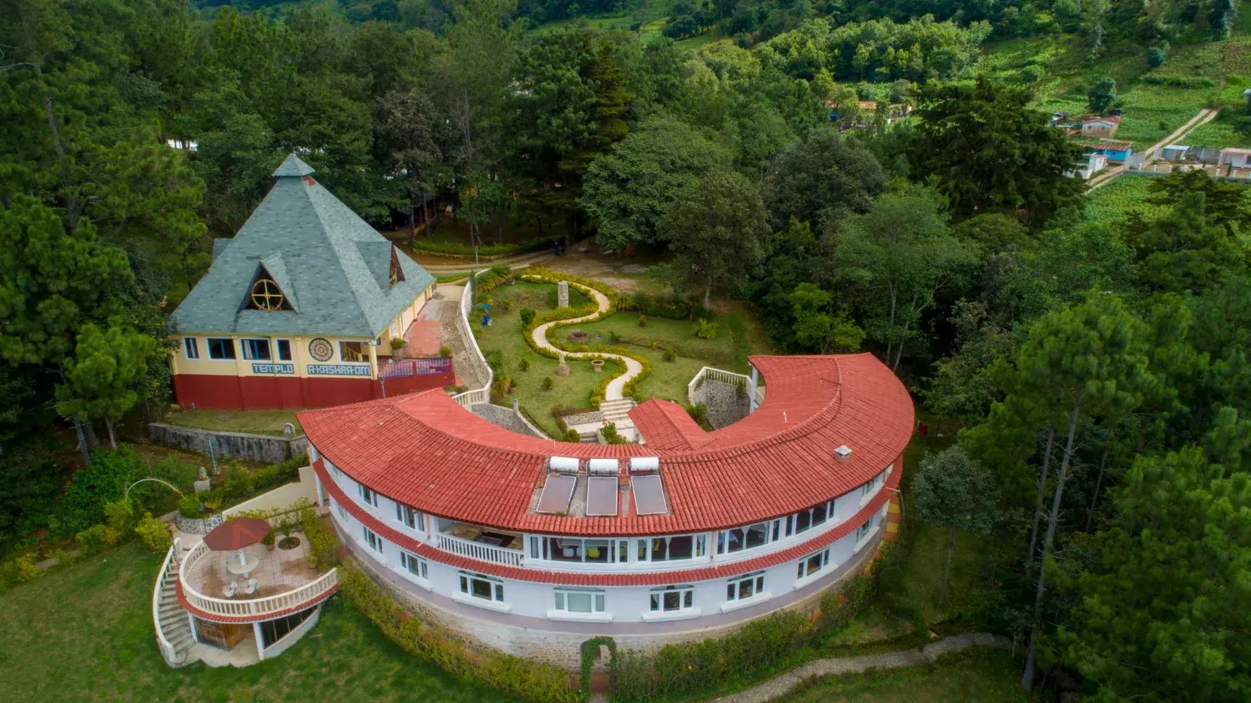 Das Zentrum Paz Mundo von oben: der geschwungene Hauptbau und der Templo A-Kashra-Om im Wald