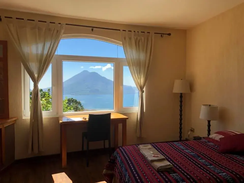 Ein Gästezimmer mit Schreibtisch am Fenster, Blick über den Atitlánsee auf den Vulkan